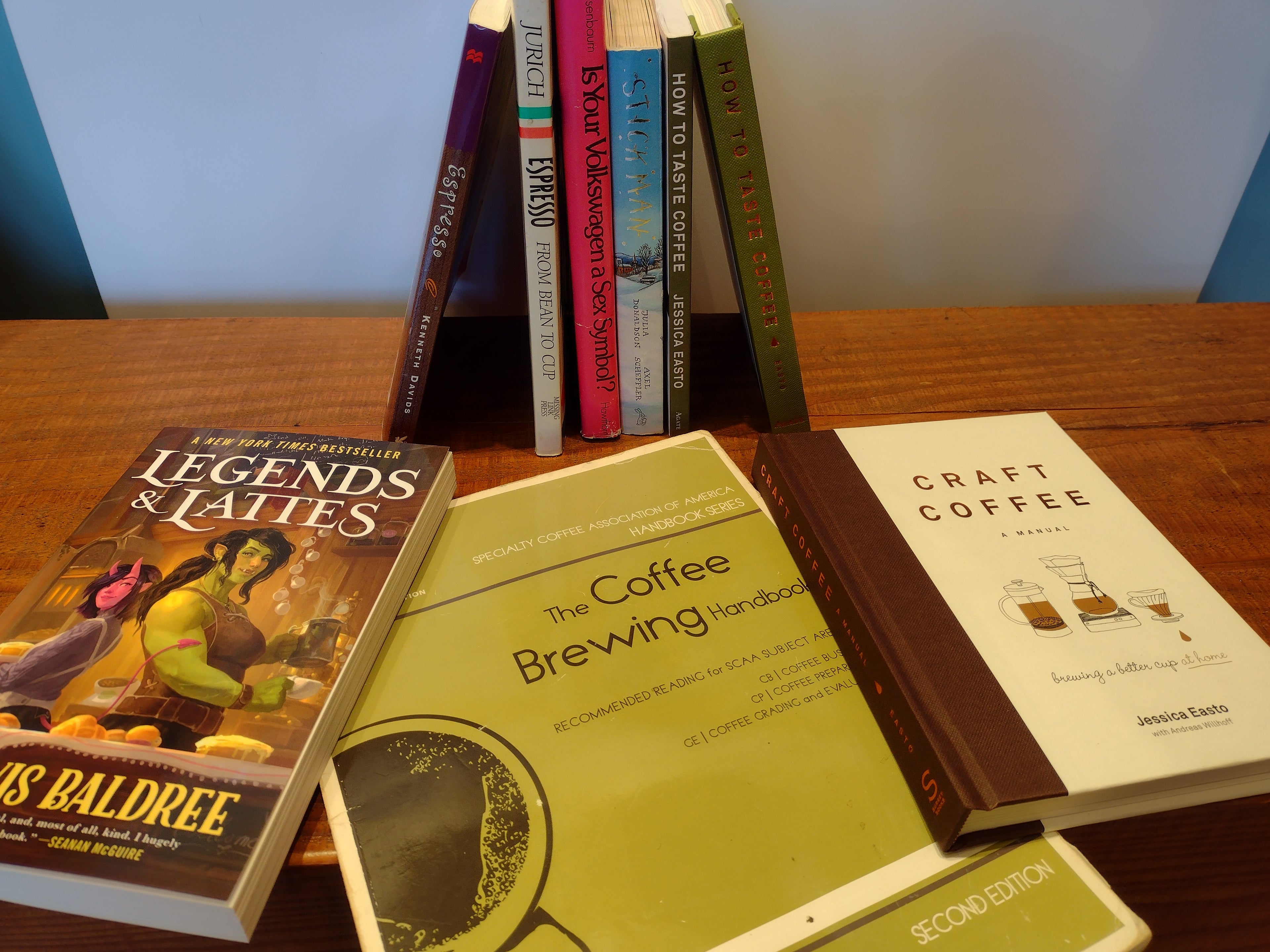 a stack of books standing upright behind a few books fanned out on a wooden surface.